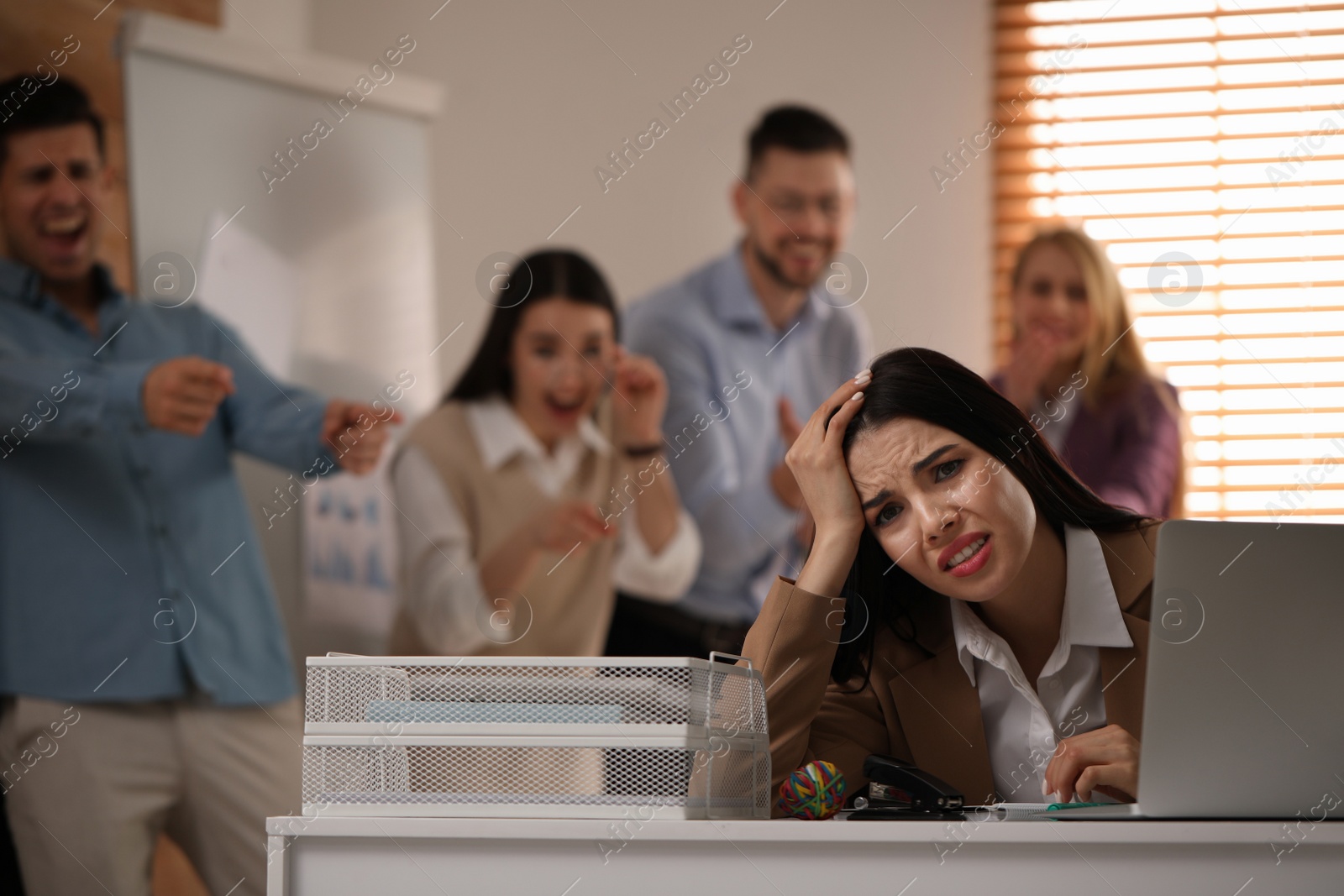 Photo of Coworkers bullying their colleague at workplace in office