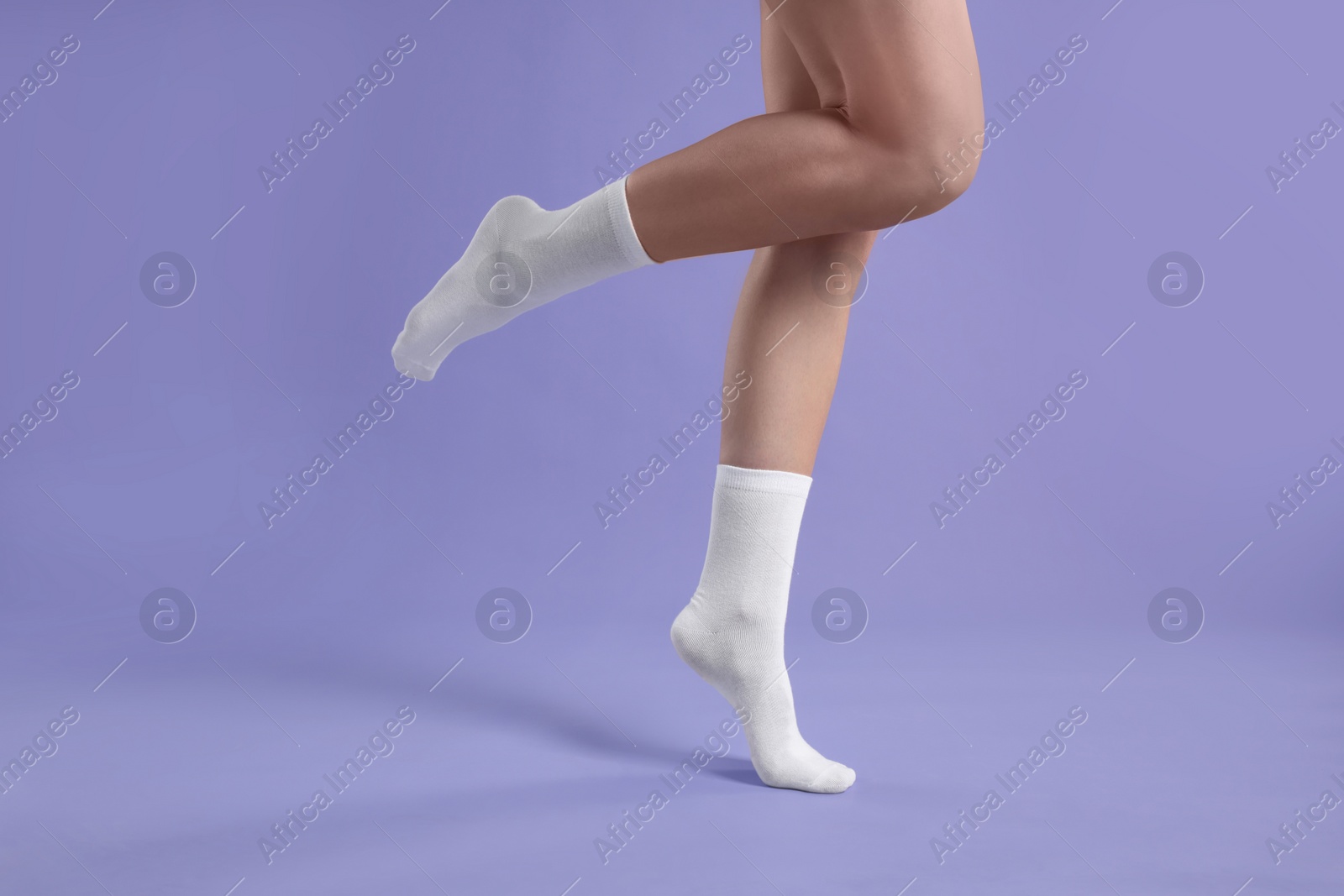 Photo of Woman in stylish white socks on violet background, closeup