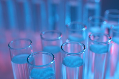 Photo of Many glass test tubes on color background, closeup