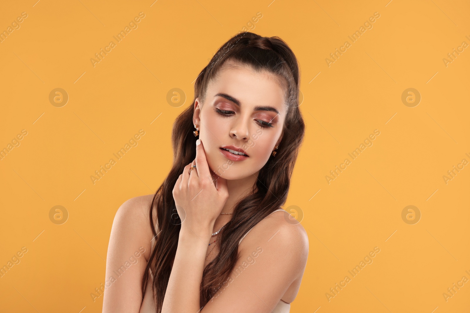 Photo of Beautiful woman with elegant jewelry on orange background