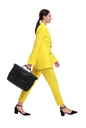 Beautiful businesswoman in yellow suit with briefcase walking on white background
