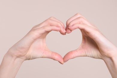 Photo of Young woman making heart with her hands on color background, closeup