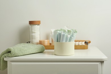 Different feminine and personal care products on white nightstand near white wall