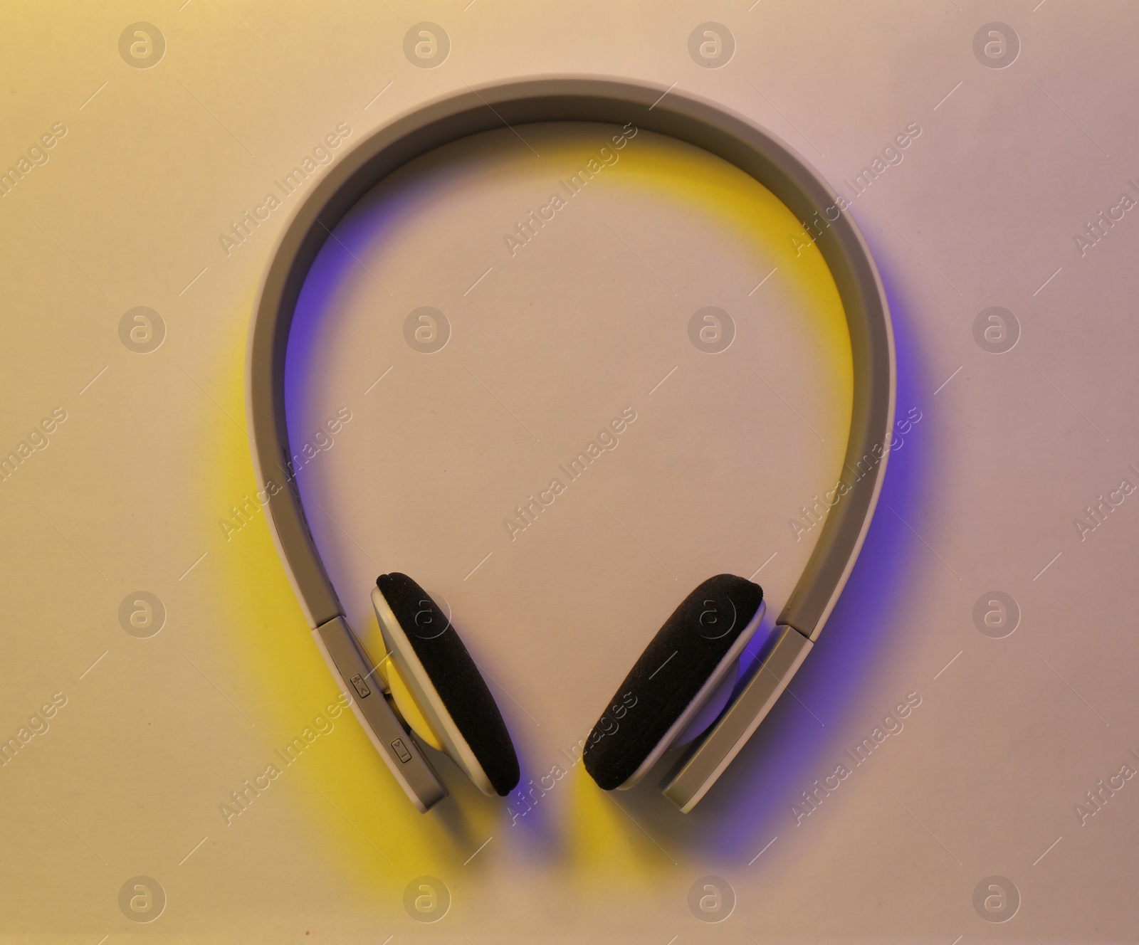 Photo of Stylish modern headphones with earmuffs on color background, top view