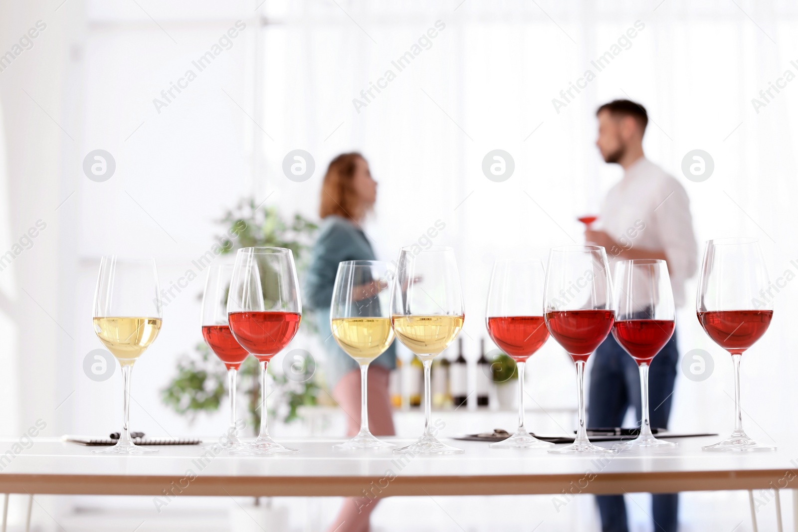 Photo of Glasses with delicious wine and blurred people on background