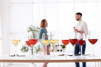 Glasses with delicious wine and blurred people on background