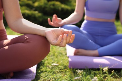 Photo of Women practicing yoga on mats outdoors, closeup