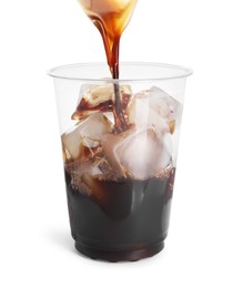 Pouring coffee into plastic cup with ice cubes on white background