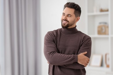 Photo of Happy man in stylish sweater at home, space for text