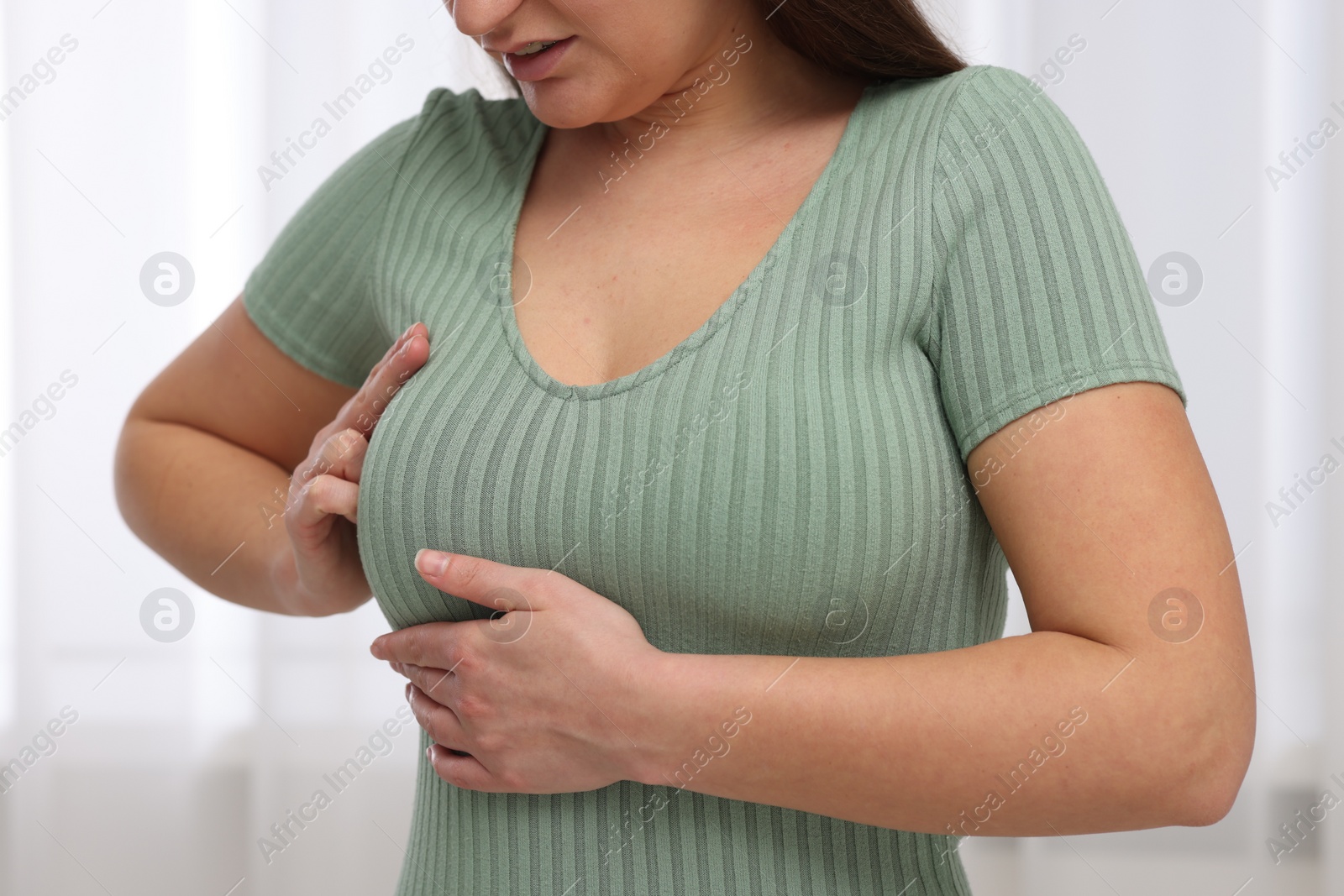 Photo of Mammology. Woman doing breast self-examination indoors, closeup