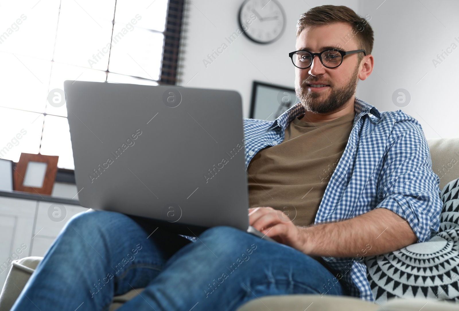Photo of Young man using laptop in living room