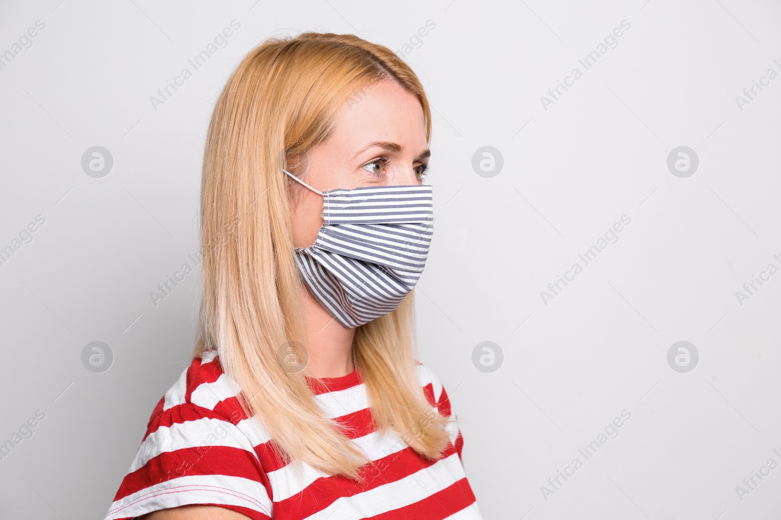 Photo of Woman wearing handmade cloth mask on white background, space for text. Personal protective equipment during COVID-19 pandemic