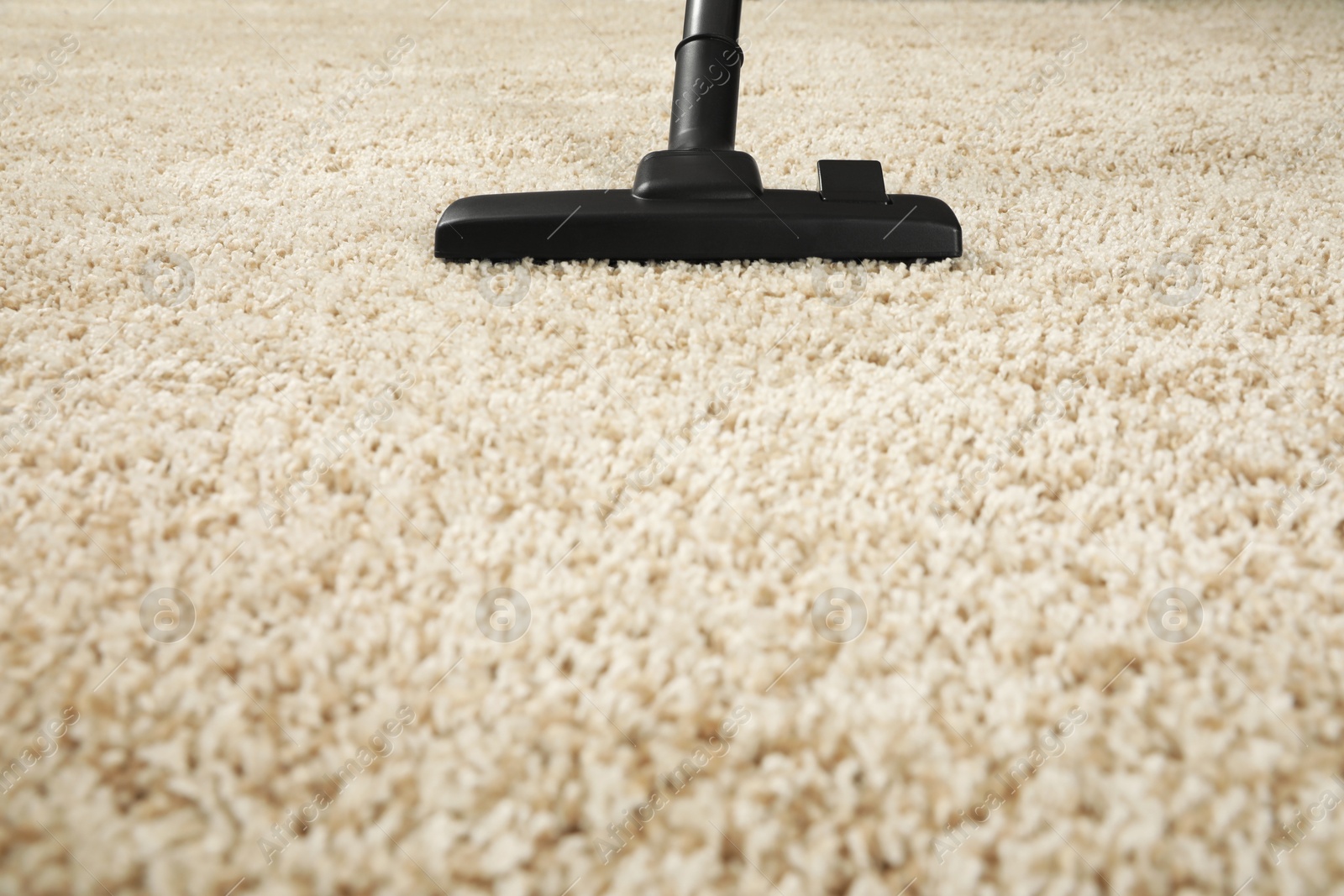 Photo of Removing dirt from beige carpet with modern vacuum cleaner. Space for text