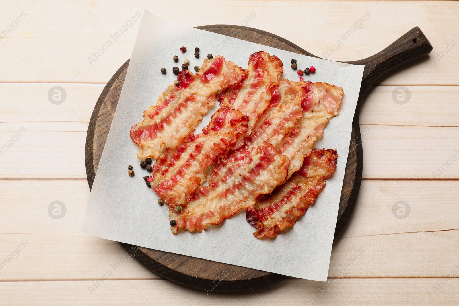 Photo of Delicious fried bacon slices on white wooden table, top view