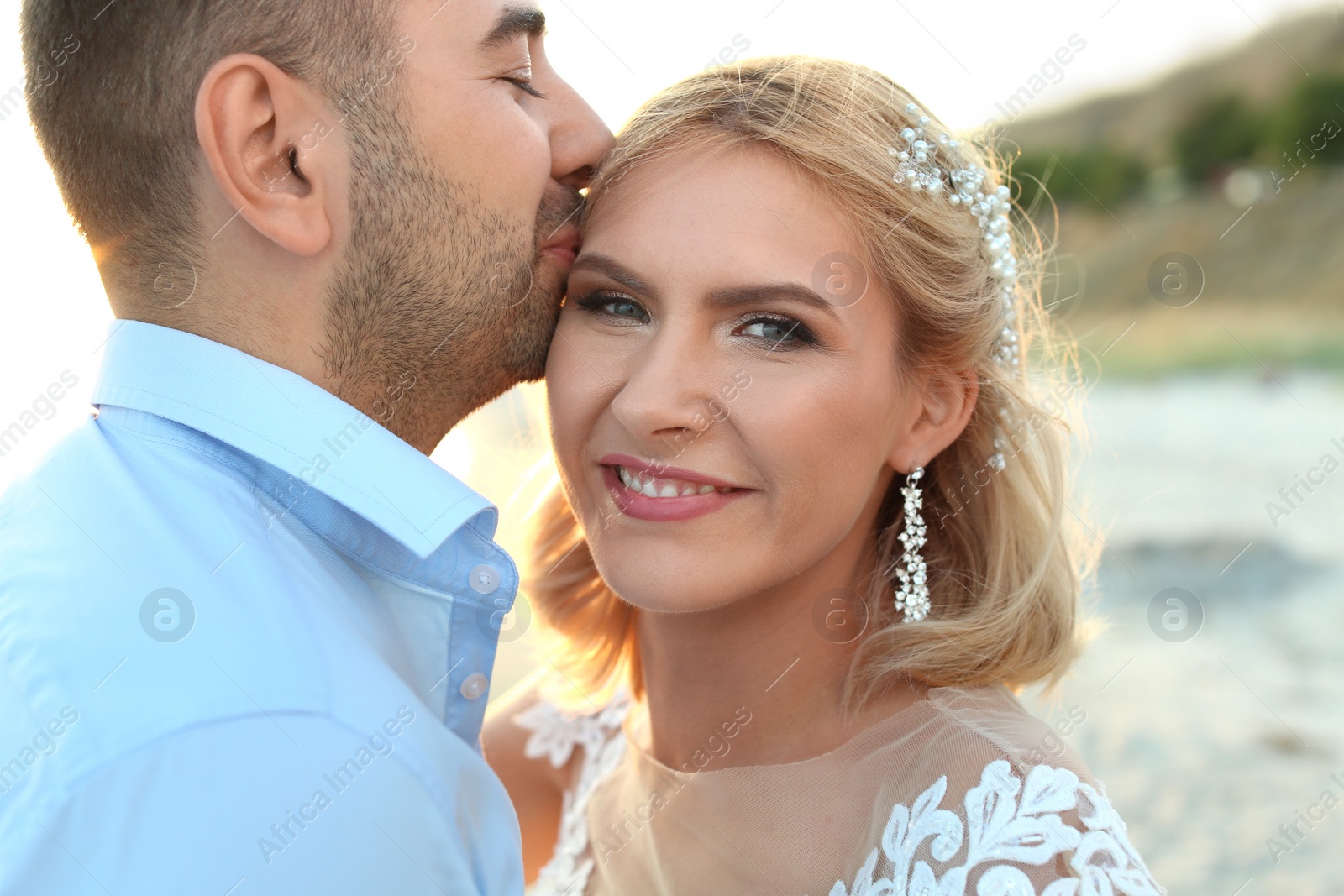 Photo of Wedding couple. Groom kissing bride on beach