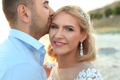 Photo of Wedding couple. Groom kissing bride on beach