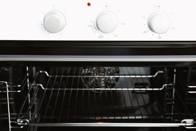 Photo of Open empty electric oven with rack, closeup