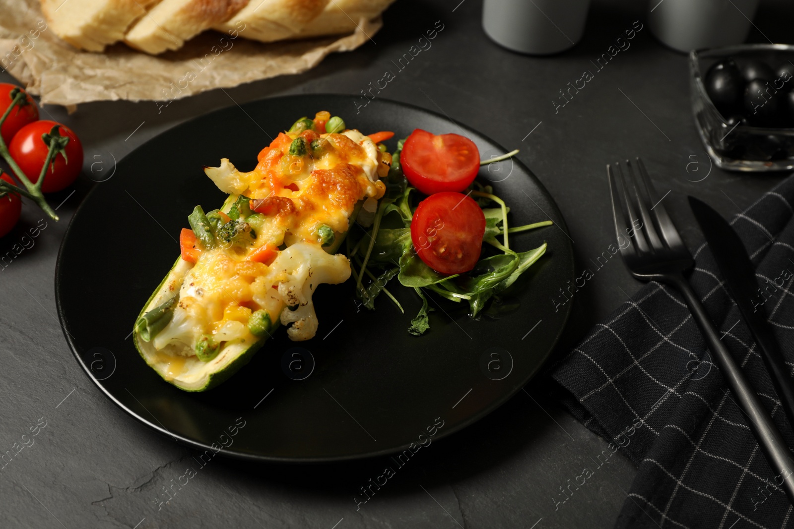 Photo of Baked stuffed zucchini served on black table, closeup