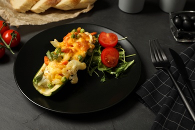 Photo of Baked stuffed zucchini served on black table, closeup