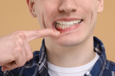 Man showing his clean teeth on beige background, closeup