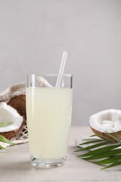 Photo of Glass of coconut water, palm leaves and nuts on light table