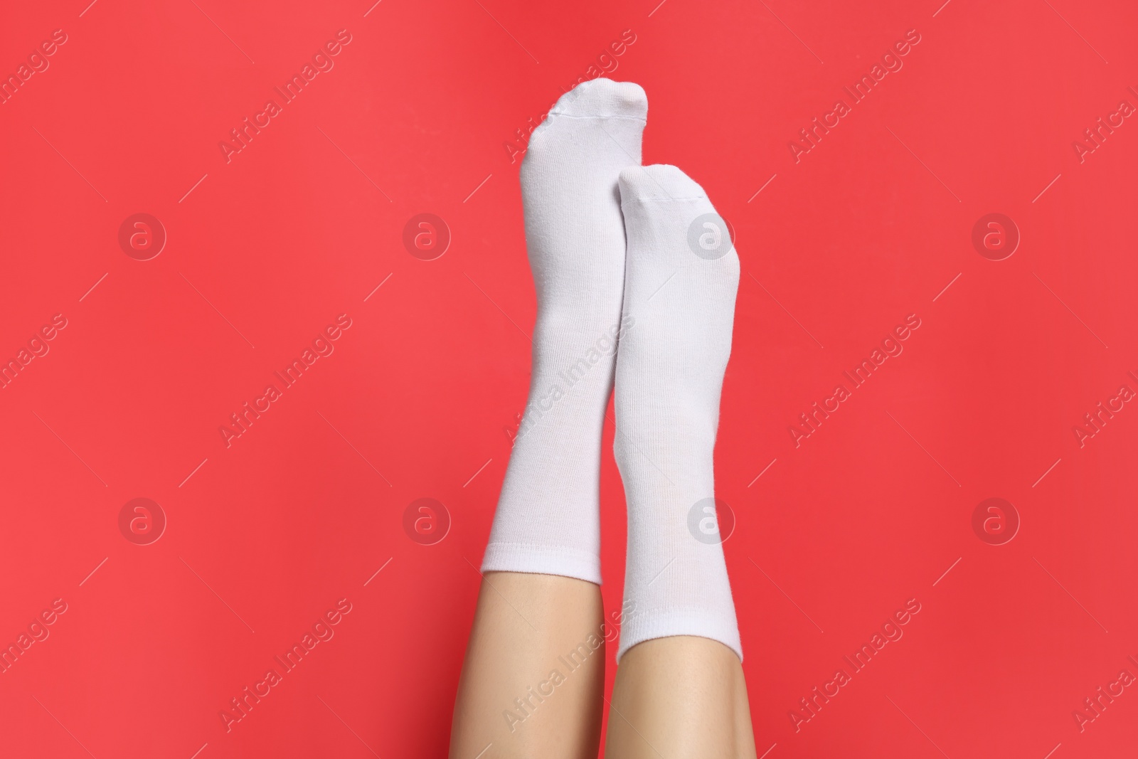 Photo of Woman in stylish white socks on red background, closeup