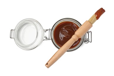 Photo of Tasty barbecue sauce in glass jar and brush isolated on white, top view