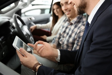 Young couple buying new car in salon