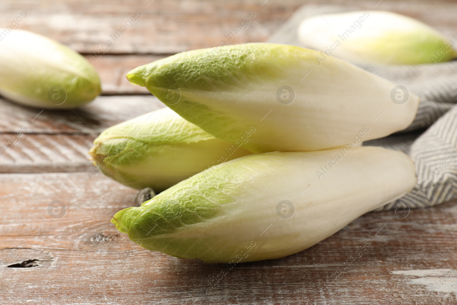 Photo of Fresh raw Belgian endives (chicory) on wooden table, closeup