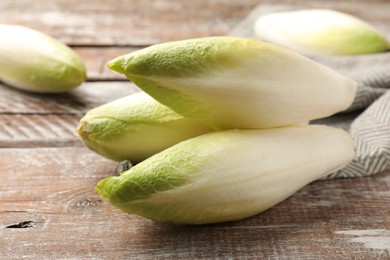 Photo of Fresh raw Belgian endives (chicory) on wooden table, closeup