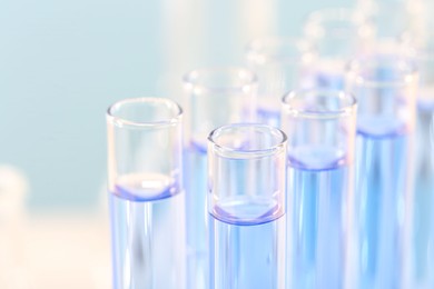 Photo of Laboratory analysis. Many glass test tubes with light blue liquid on blurred background, closeup and space for text