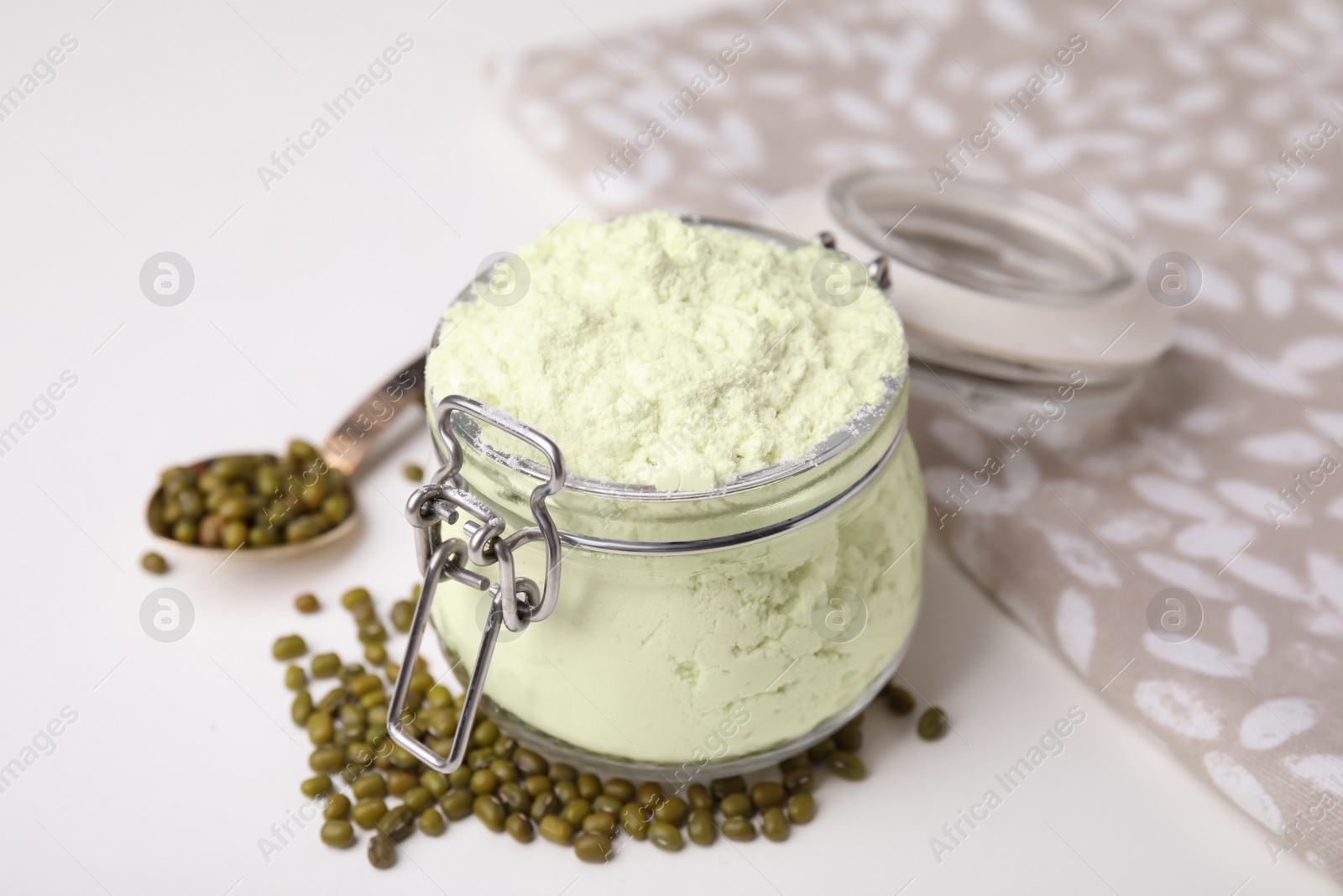 Photo of Glass jar of flour and mung beans on white table