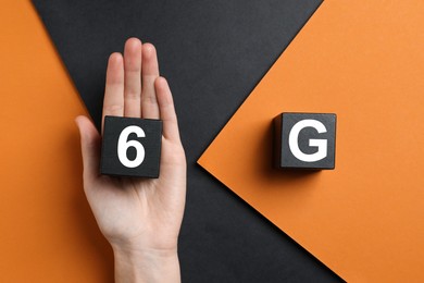 6G technology, Internet concept. Woman with black wooden cubes on color background, top view