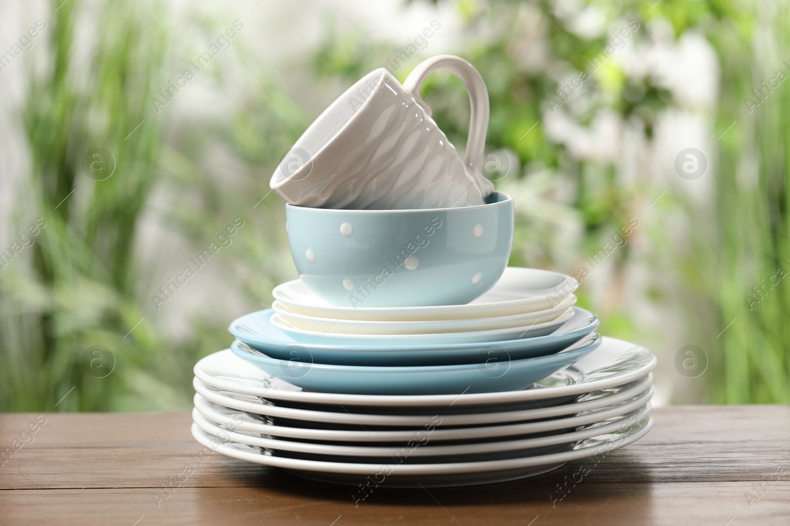 Photo of Beautiful ceramic dishware and cup on wooden table outdoors