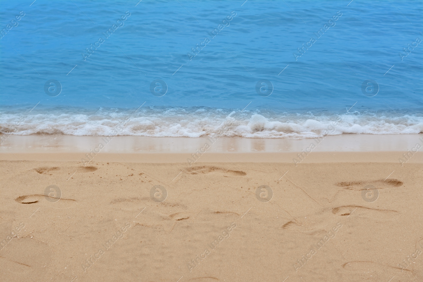 Photo of Sandy beach with footprints near beautiful sea