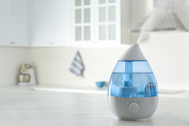 Modern air humidifier on marble table in kitchen. Space for text