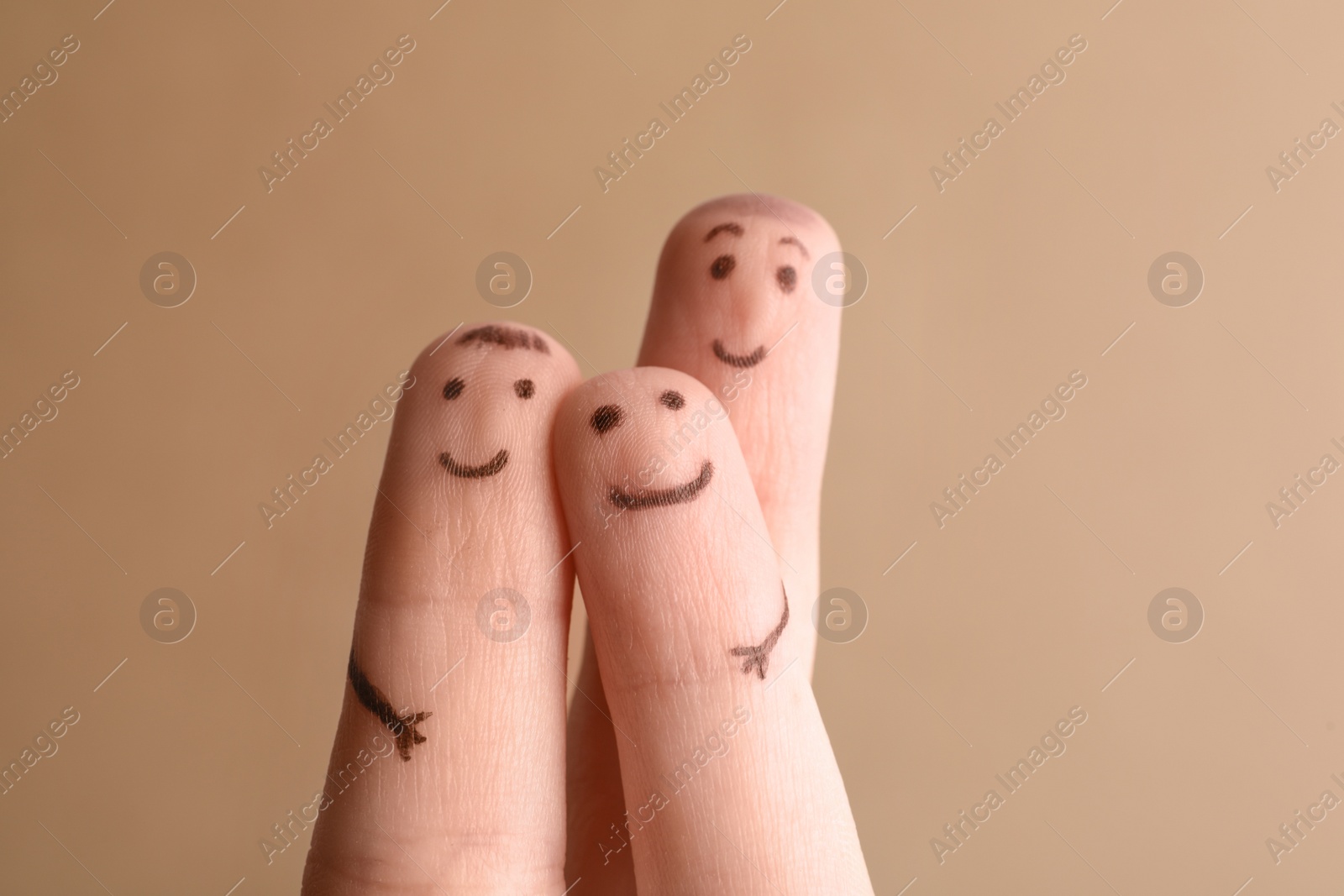 Photo of Three fingers with drawings of happy faces on brown background. Family time