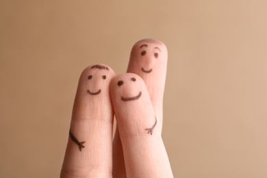 Photo of Three fingers with drawings of happy faces on brown background. Family time