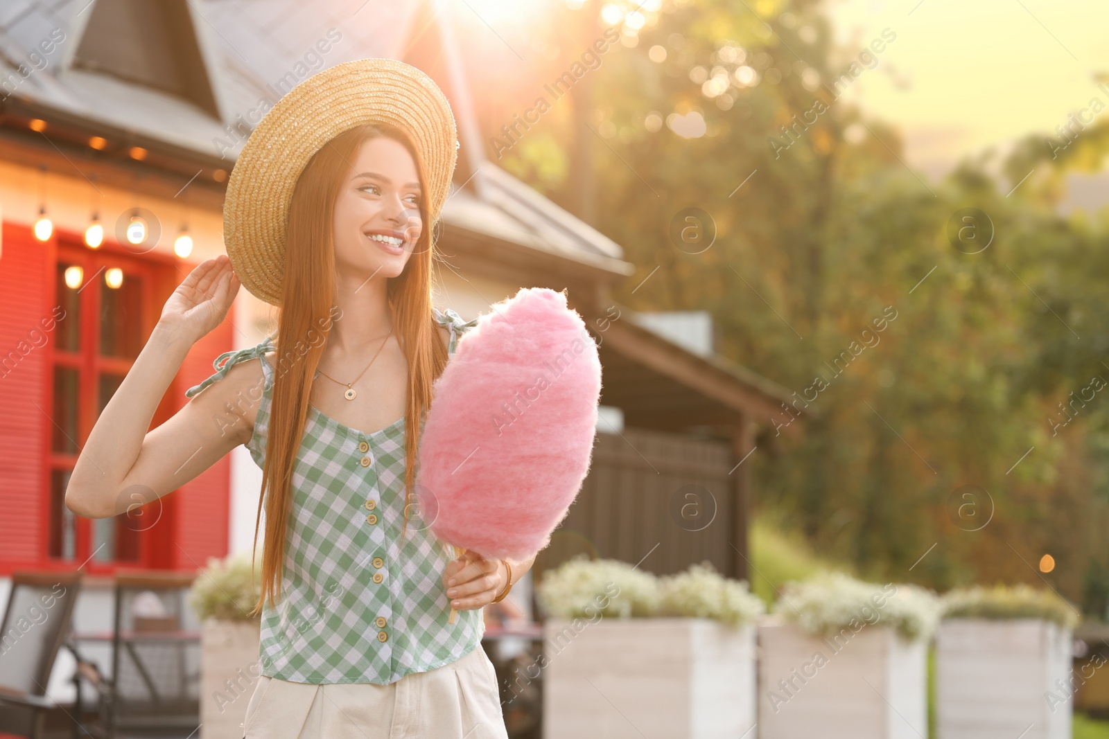 Photo of Smiling woman with cotton candy outdoors on sunny day. Space for text