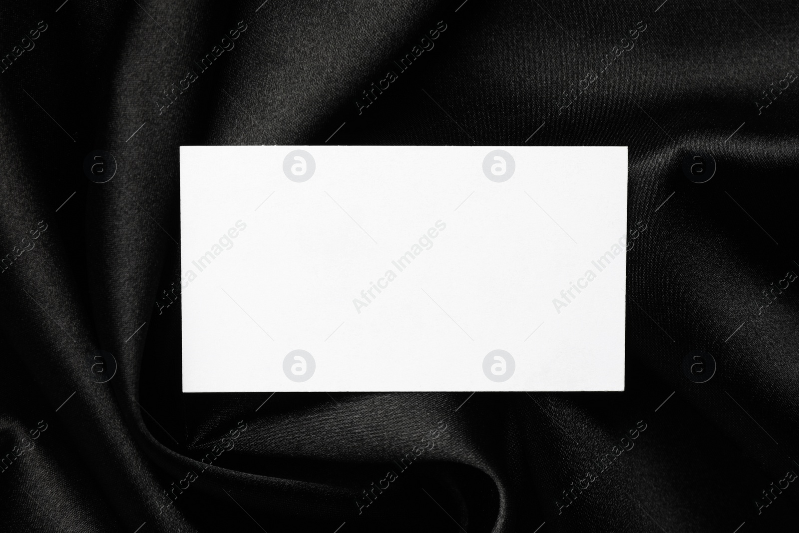 Photo of Blank business card on black fabric, top view. Mockup for design