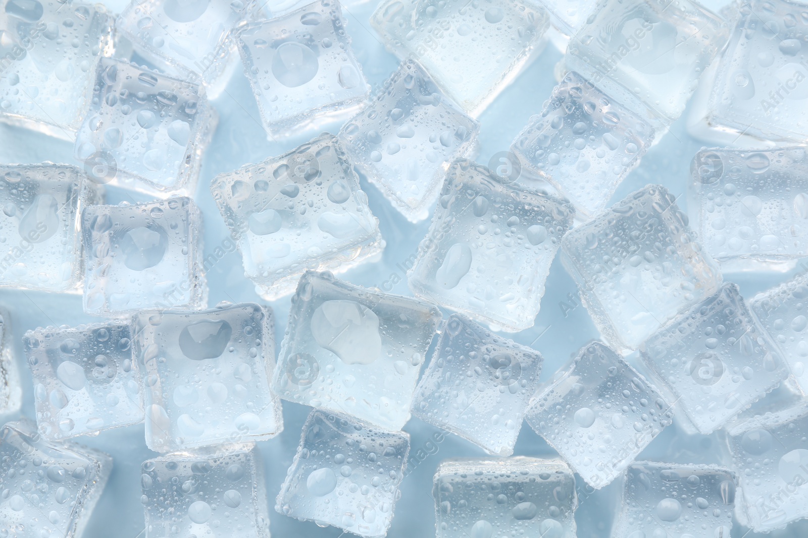 Photo of Crystal clear ice cubes on light blue background, flat lay