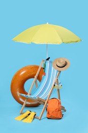 Photo of Deck chair, backpack and beach accessories on light blue background