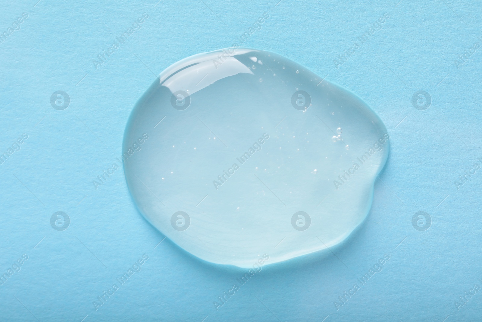 Photo of Drop of ointment on light blue background, top view