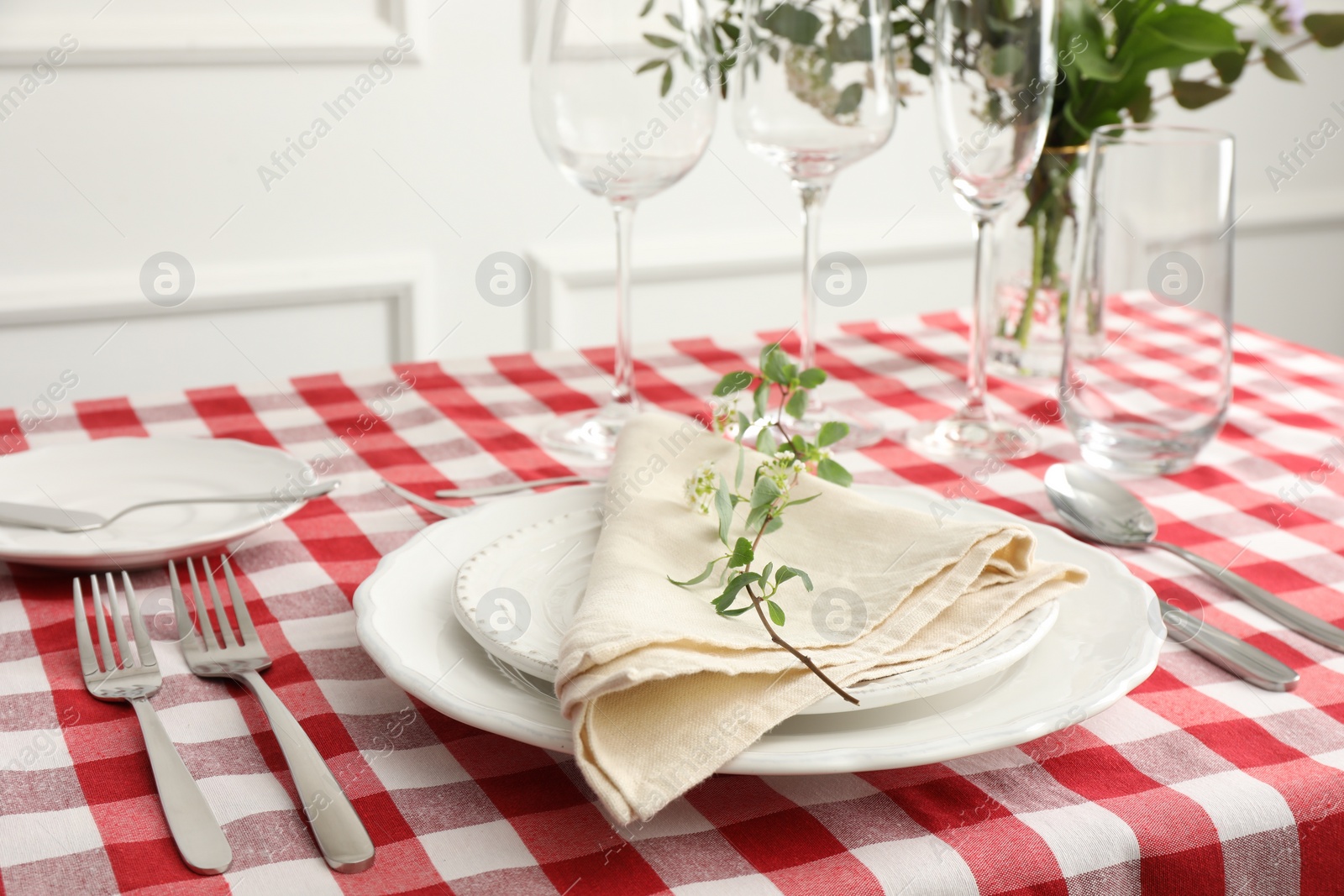 Photo of Stylish setting with cutlery, plates, napkin, glasses and floral decor on table