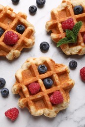 Photo of Delicious Belgian waffles with fresh berries and mint on white marble table, flat lay