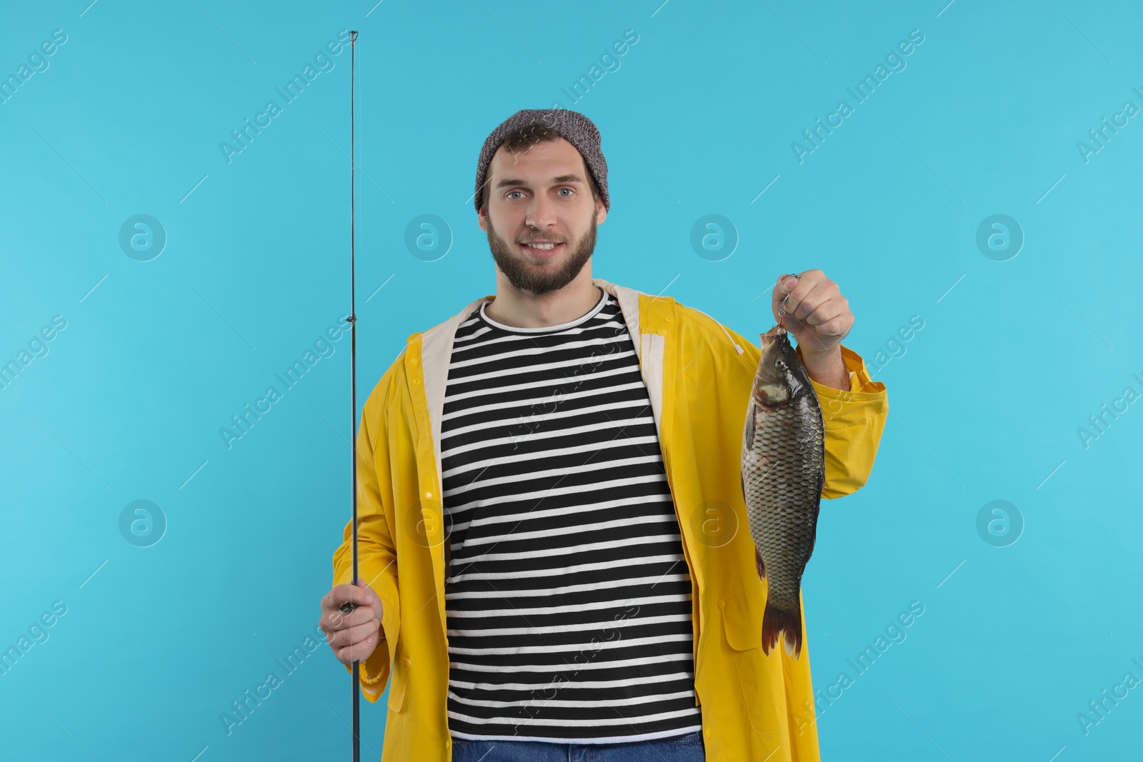 Photo of Fisherman with rod and catch on light blue background