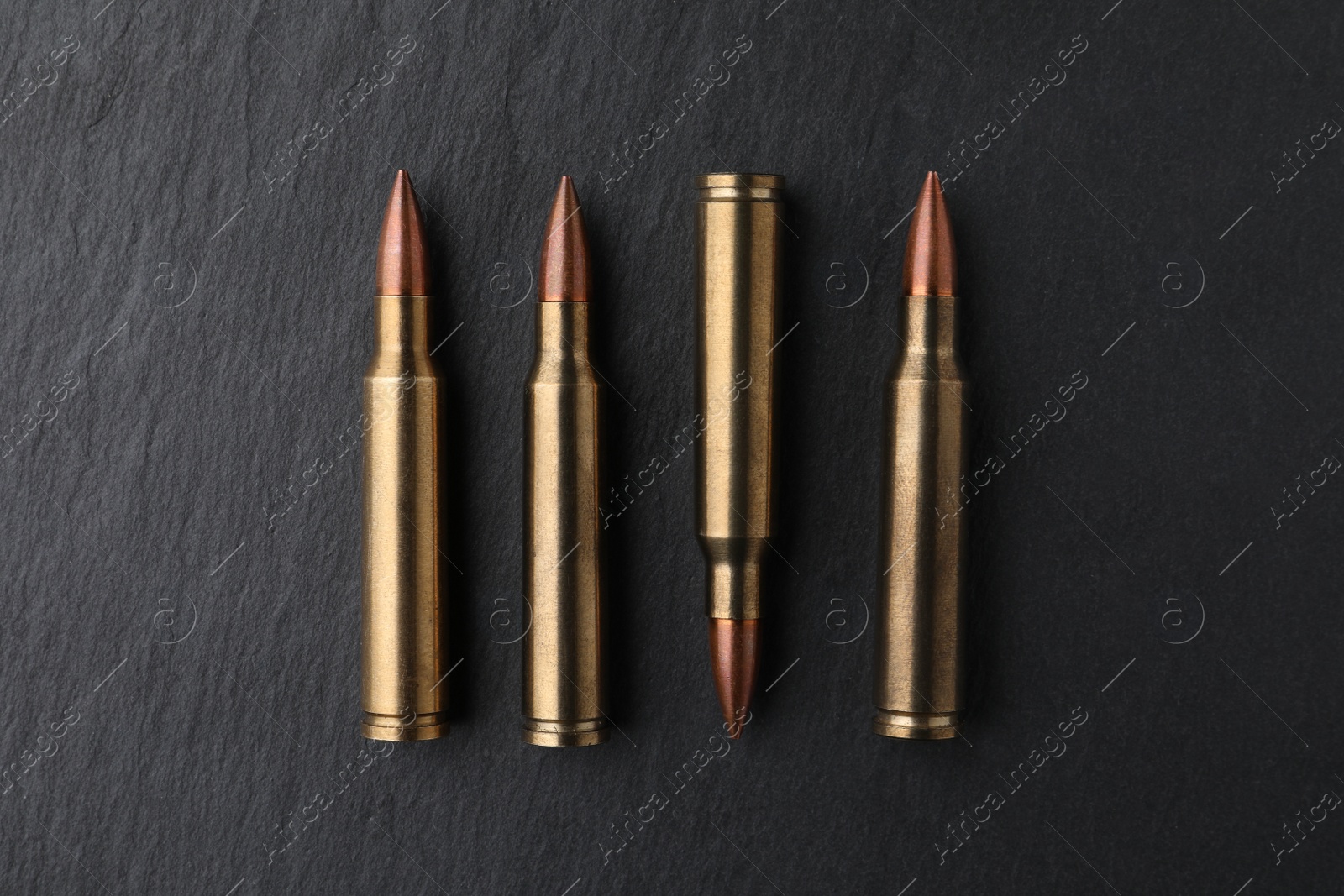 Photo of Many bullets on black table, flat lay. Military ammunition