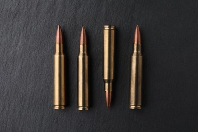 Photo of Many bullets on black table, flat lay. Military ammunition