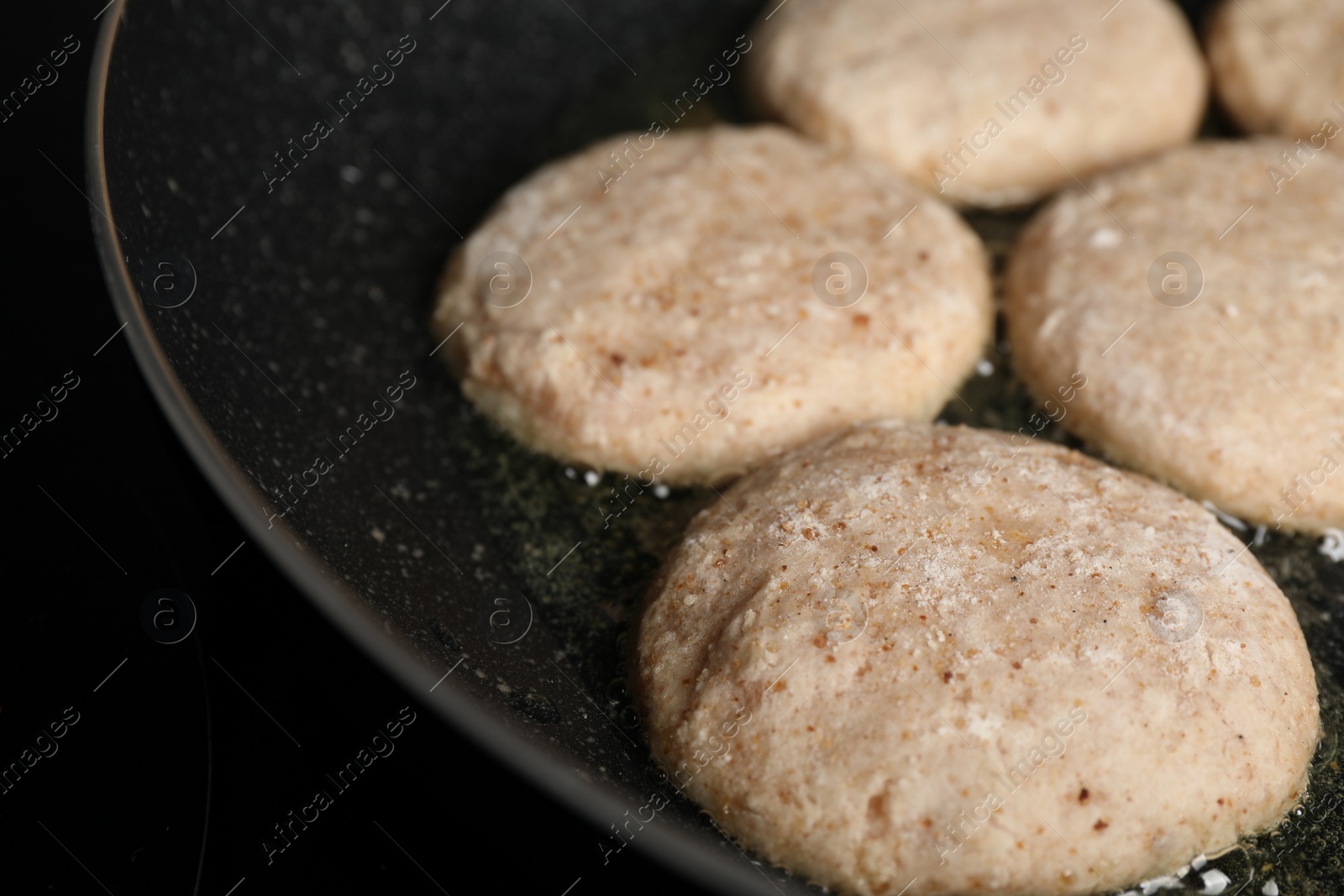 Photo of Cooking vegan nuggets in frying pan on cooktop, closeup