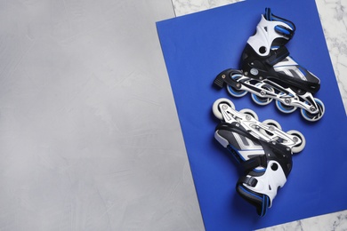 Photo of Pair of inline roller skates on color background, top view with space for text